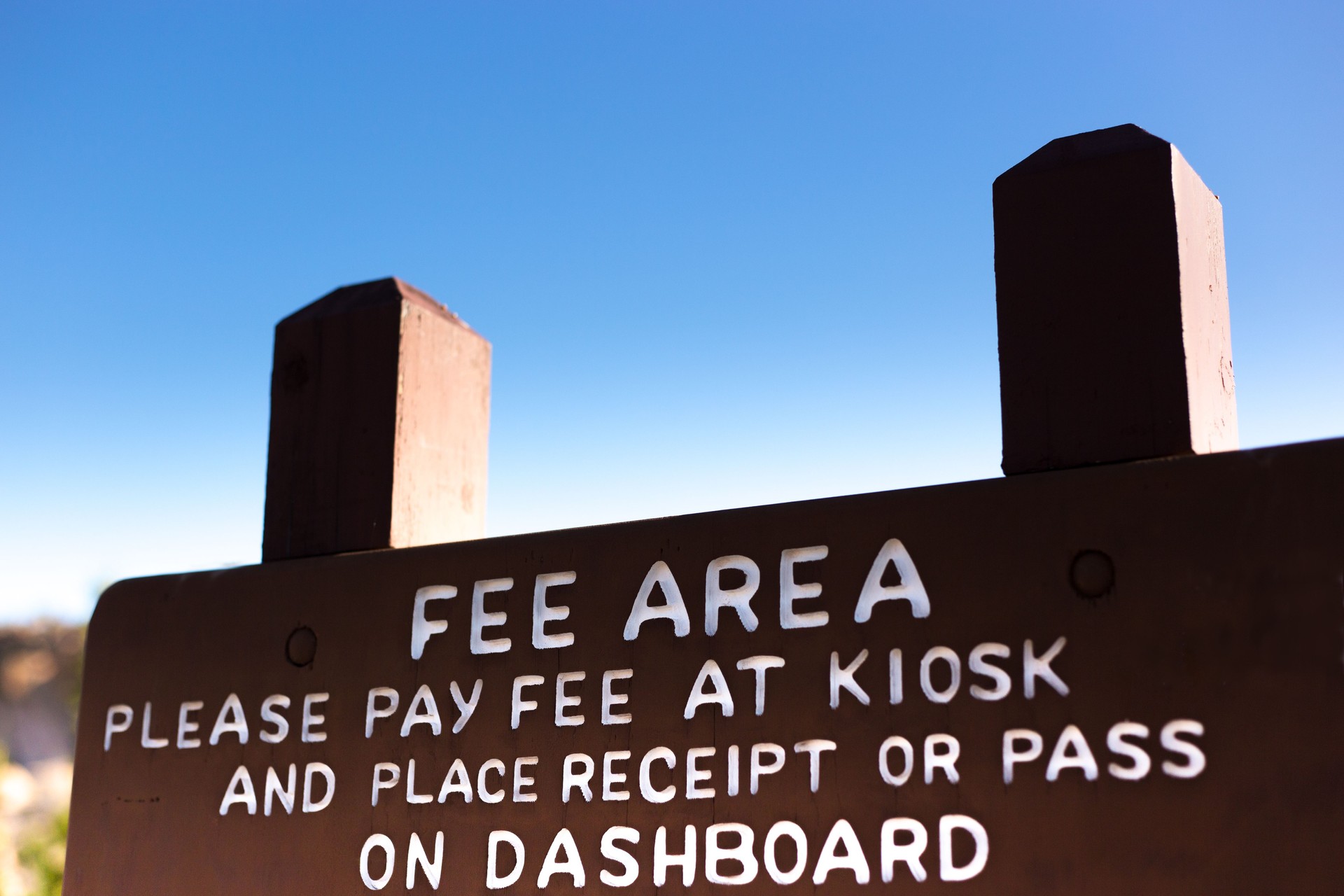 Wooden Sign in Wilderness Park:"PAY FEE AT KIOSK"